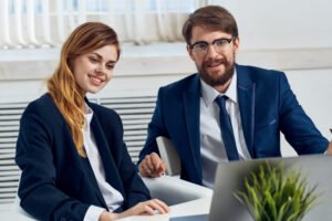 Business man and woman in suit with laptop and flower potted office staff communication